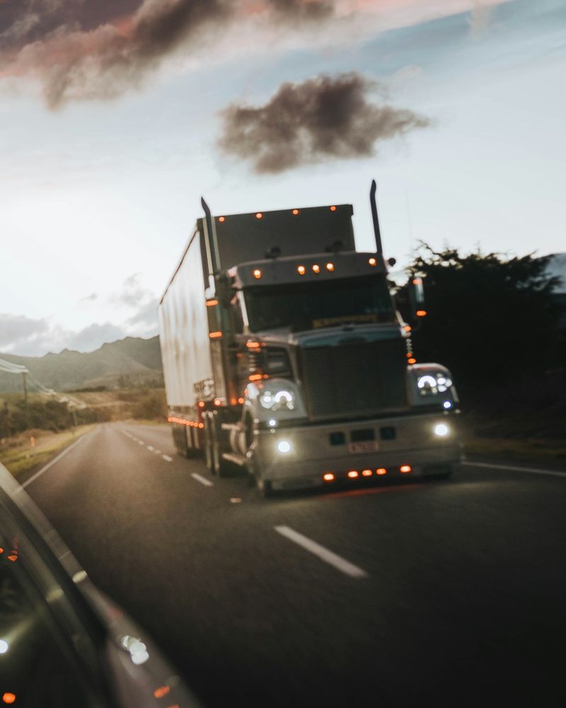 Semi truck with headlights on, on the highway at dusk