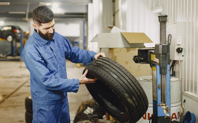 Technician inspecting a tire beside a tire changer
