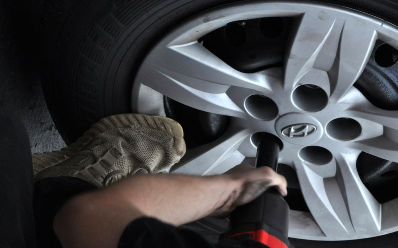 Impact wrench removing the wheel nuts on a passenger car
