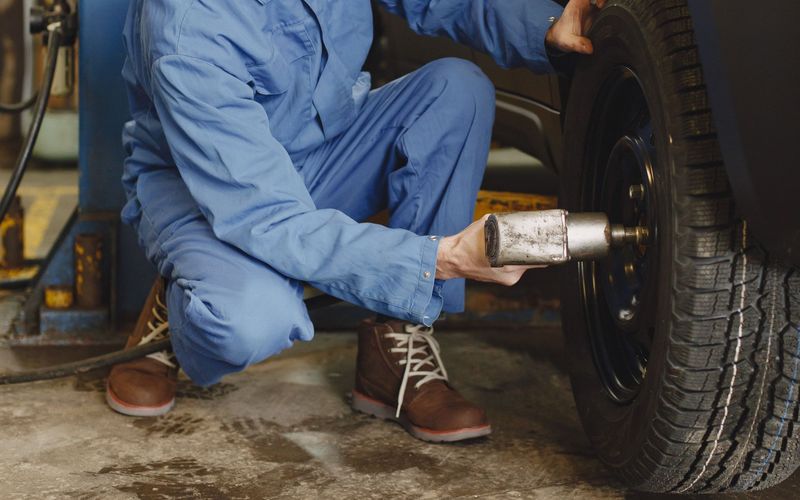 Technician fitting a wheel onto a vehicle with an impact wrench
